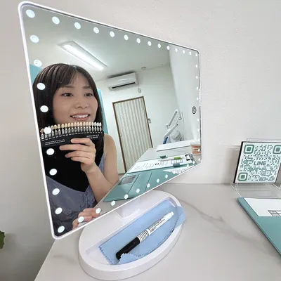 鏡の前で色見本を使い歯の色を確かめるお客様