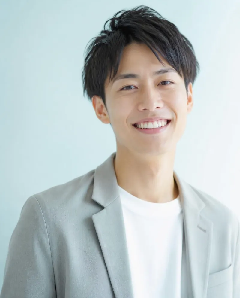 白い歯を見せて笑う男性のイメージ写真